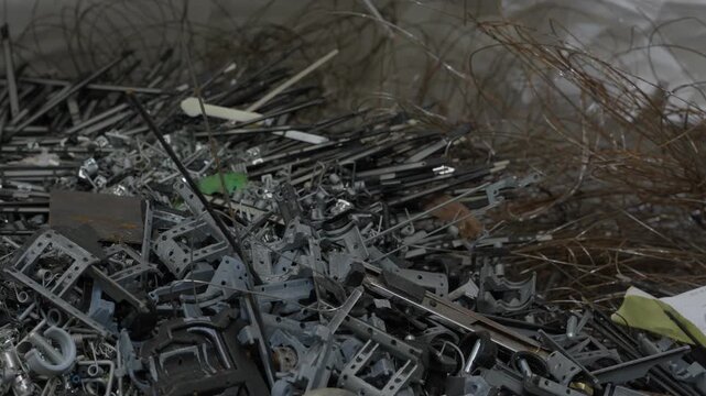Large pile of mixed metal scrap brackets components and tangled wire collected for recycling processing