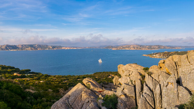 Sunset panoramic view of La Maddalena Archipelago with Santo Stefano Island and a small white ferry passing to the island, Sardinia Island, Italy