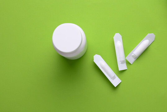 Rectal suppositories and pills bottle on a green background
