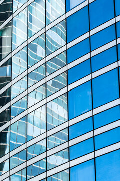 Corporate office building with modern glass facade windows blue reflections and pattern showing architecture detail for business background in daylight