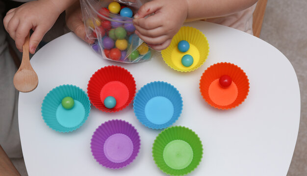 Little baby play with Color sorter,  balls and plates on a table. Developing motor skills and color differences.