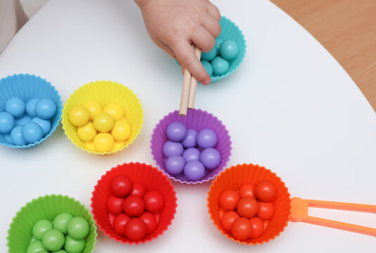 Little baby play with Color sorter,  balls and plates on a table. Developing motor skills and color differences.