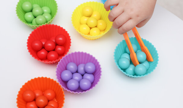 Little baby play with Color sorter,  balls and plates on a table. Developing motor skills and color differences.