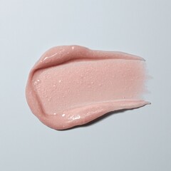 Fototapeta premium A smooth stroke of soft pink cream is swiped across a clean white surface, demonstrating its rich and hydrating texture for skincare application