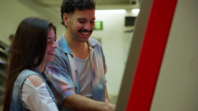 Young happy couple buying subway tickets at station kiosk