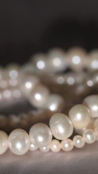 Elegant pearl strands arranged on neutral background, symbol of luxury and refinement.
Close-up of pearl strands arranged in layered composition on a neutral gray background. Vertical.