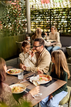 Father and Daughters Sharing Pizza on Outdoor Restaurant Patio During Casual Family Lunch