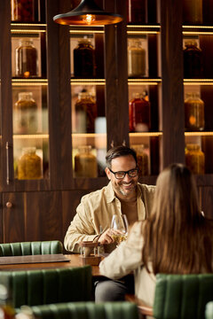 Smiling Man and Woman Enjoying Date Night Wine and Conversation in Cozy Restaurant Interior