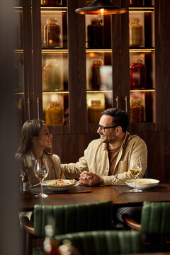 Smiling Father and Daughter Sharing a Cozy Restaurant Dinner With White Wine and Conversation