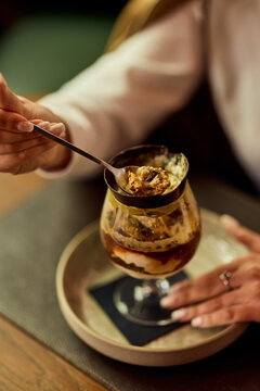 Woman Tasting Decadent Dessert in Cafe Glass Cup During Cozy Brunch Moment With Elegant Hands