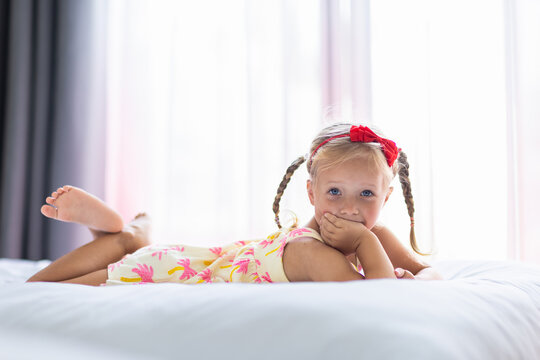 Young girl lying on a bed with a red headband and braids