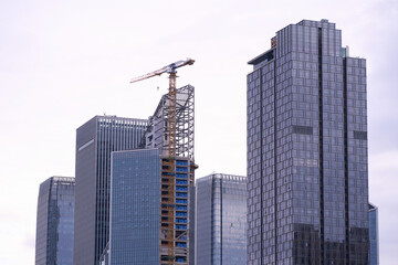 Naklejka premium Modern skyscrapers and construction crane in urban cityscape