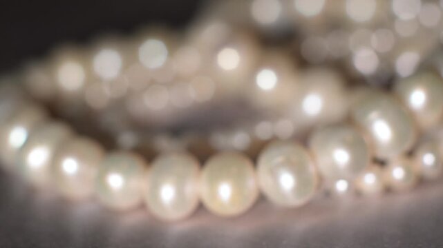 Pearl necklace strands on soft gray background, bridal elegance concept.
Delicate pearl strands arranged in soft composition on a neutral gray background.