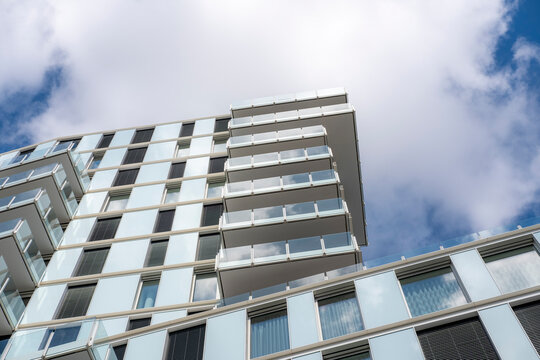 Perspective and glass windows define a modern urban architecture building facade under sky and clouds offering calm editorial background copy space