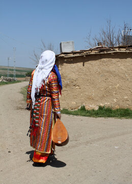An Anatolian woman in local attire, holding a Turkish instrument called the bağlama (saz).