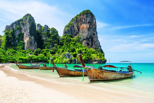 Longtail Boats on amazing Railay Beach in Krabi province. Ao Nang, Thailand. Scenic Railay Beach with traditional boats, turquoise water and limestone cliffs in Krabi.