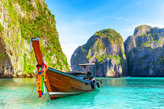 Longtail Boat in Maya Bay Lagoon, Phi Phi islands in Thailand. Tropical scenery of Maya Bay with traditional longtail boat, turquoise water and dramatic limestone cliffs