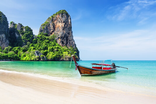 Traditional longtail boat and turquoise water on Railay Beach in Krabi, Thailand. Scenic Railay Beach with traditional boats, turquoise water and limestone cliffs.