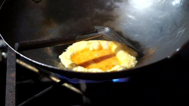 Cooking an egg in a hot pan as a complement to delicious and simple homemade fried rice.