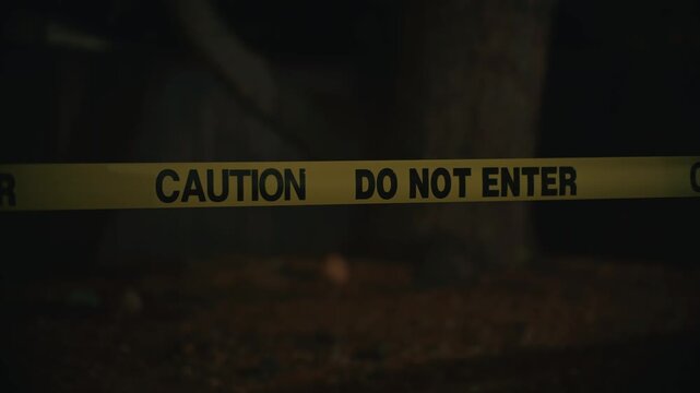 Yellow caution tape do not enter blocking dangerous area at night indicating restricted access and zone safety in dark outdoor environment