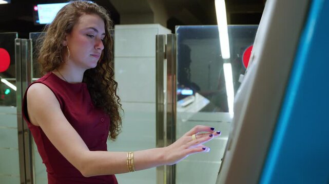 Young woman buying subway ticket at vending machine