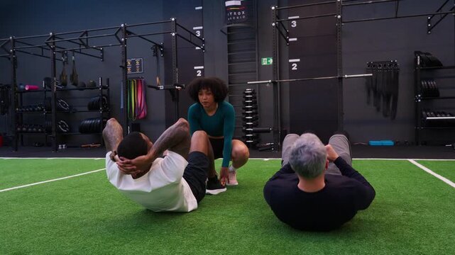 Female personal trainer coaching two men doing crunches
