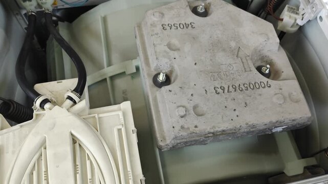 Close-up of wiring and concrete weights inside a modern washer