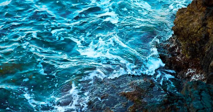 Onde con schiuma che urtano delle rocce a riva 