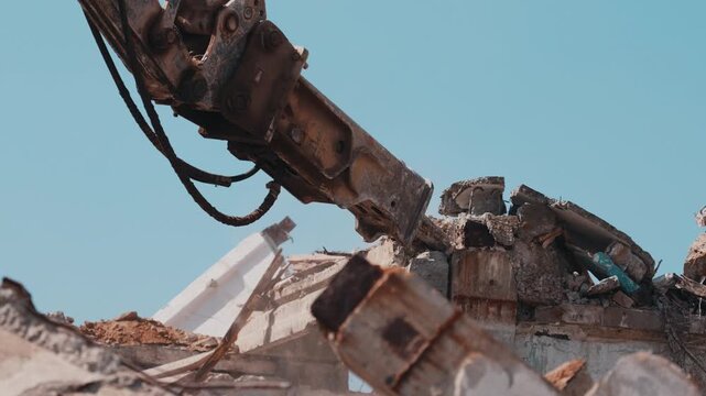 Excavator hydraulic hammer breaking concrete structure during demolition close up