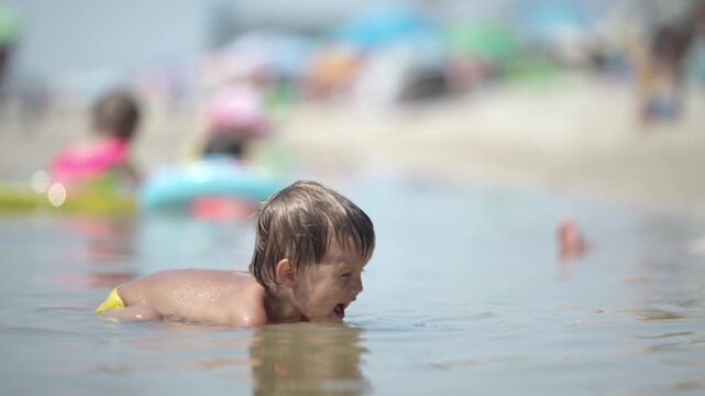Kid collects shells and pebbles in the sea on a sandy bottom under the summer sun on a vacation