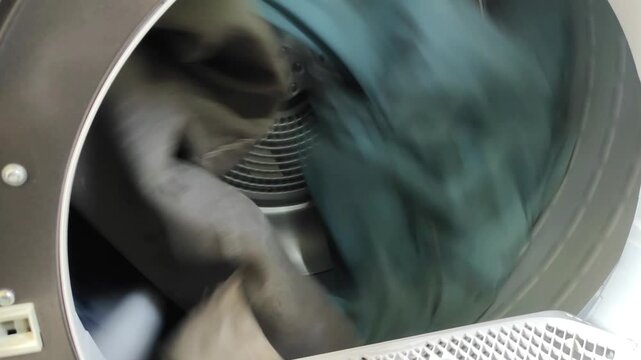 Modern tumble dryer drum spinning with wet clothes inside