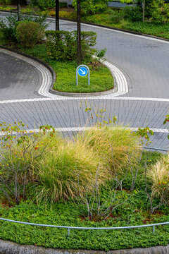 Roundabout sign at junction shows island curb lane and roadway layout for urban traffic navigation and safe driving in daylight scene