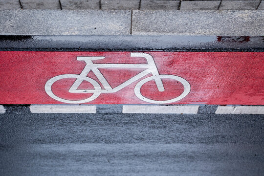 Red pavement bicycle symbol marking on asphalt shows bike lane for urban transport and commuting on city street in daylight with detail texture