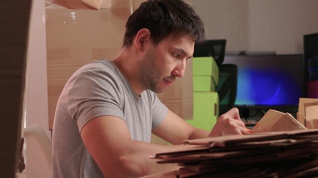 Man packs swiftly. Worker rapidly assembling and sealing packages at busy station. Energetic individual quickly folding and locking tabs on cardboard boxes for shipping