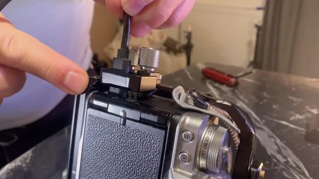 Hands installing USB-C cable on camera cage close-up, connecting power or data interface for external devices, ensuring stable operation during filming setup and professional video production workflow