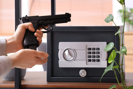 Woman reloading pistol near safe on shelf at home, closeup