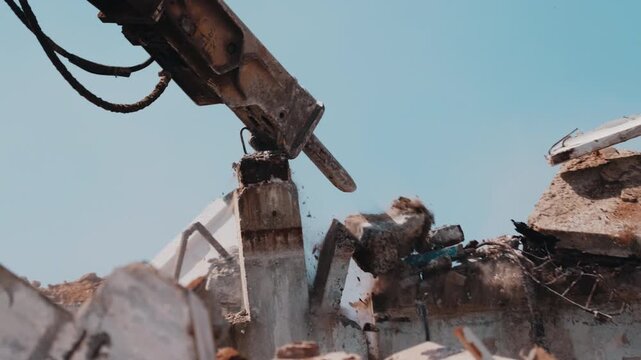 Excavator hydraulic hammer breaking concrete column during demolition close up