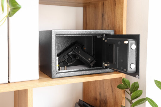 Open safe with pistol, bullets and money on shelf at home