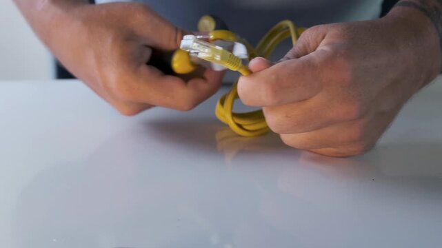 Male hands cutting ethernet cable with pliers, concept of internet shutdown, network failure or cyber security disruption, close up of data connection being physically disconnected