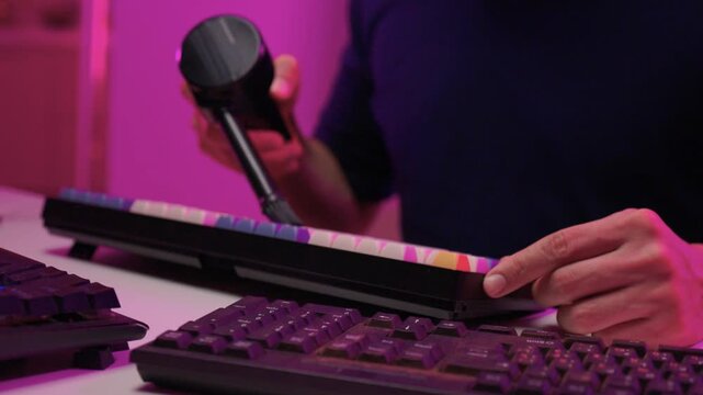 Individual examines dust buildup on gaming equipment thoroughly. Person meticulously maintains computer hardware in vibrant gaming environment with focused attention