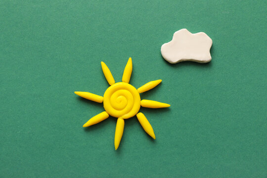 Cute sun and cloud made of plasticine on green background