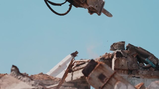 Excavator hydraulic breaker smashing concrete debris during demolition close up