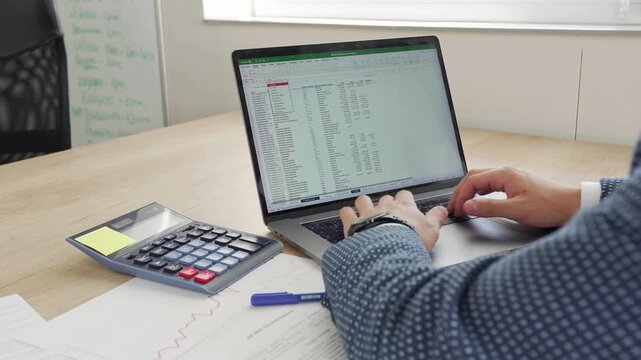 Businessman analyzing financial data on a laptop spreadsheet with a calculator