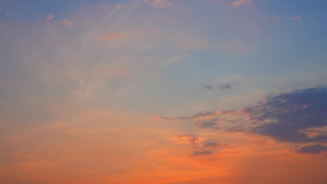 A sunset sky timelapse video footage featuring thin cirrus and scattered stratocumulus clouds glowing in warm orange tones, capturing smooth gradients, soft motion and atmospheric transitions at dusk.
