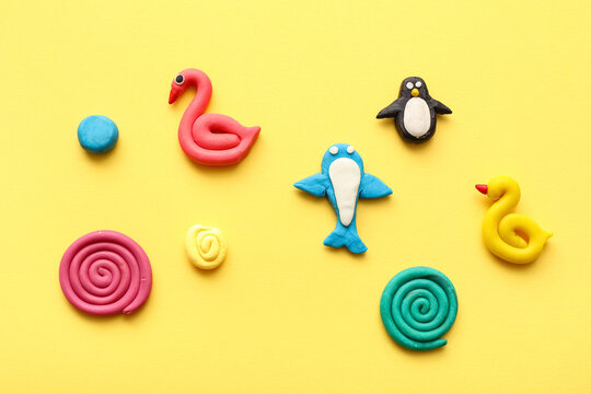 Different figurines with colorful plasticine spirals on yellow background