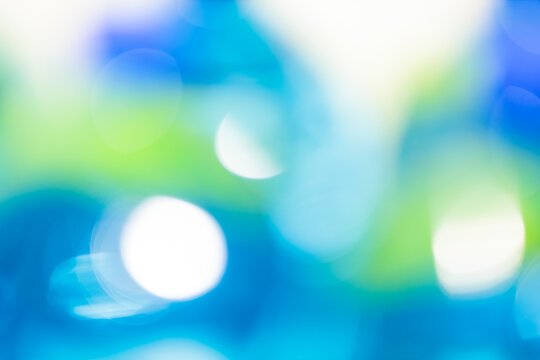 Abstract blue and green bokeh background with glowing white circles and soft defocused light effect