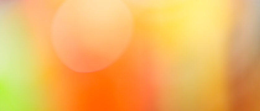 Vibrant orange and yellow bokeh abstract background with green accent and glowing light circle