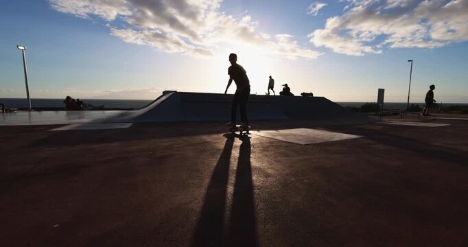 Young people having fun at skateboard park outdoor during sunset time - Summer lifestyle, boys and extreme sport concept - UGC wide lens content