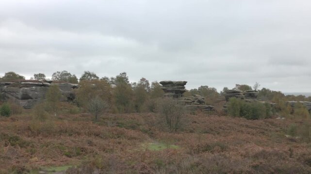 panning shot of large rock formations with tourists at Brimham rocks