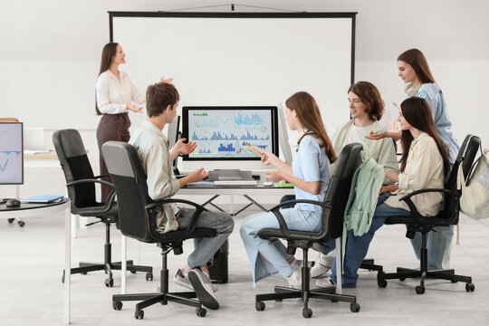 Teenage students with teacher studying at school computer lab
